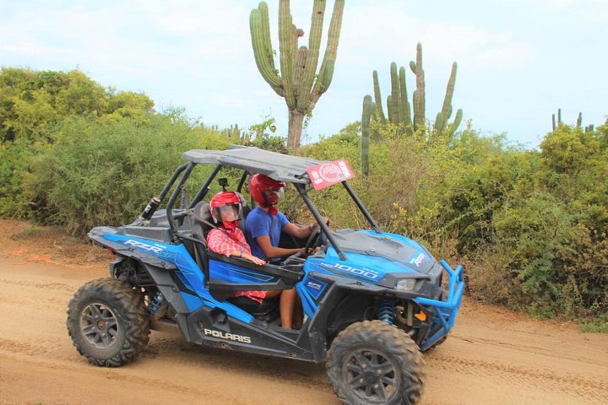 due persone a bordo di un quad blu su una strada sterrata