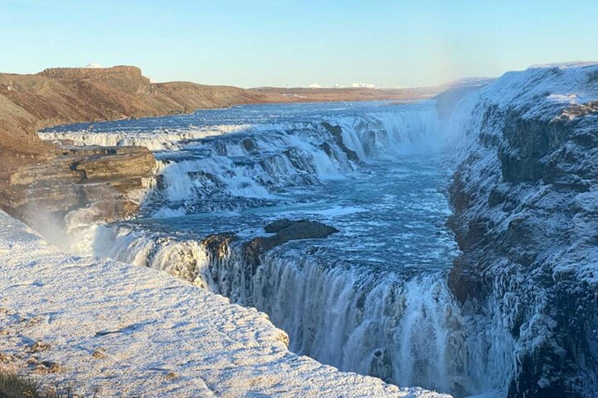 ein Wasserfall auf einer Klippe mit Schnee darauf