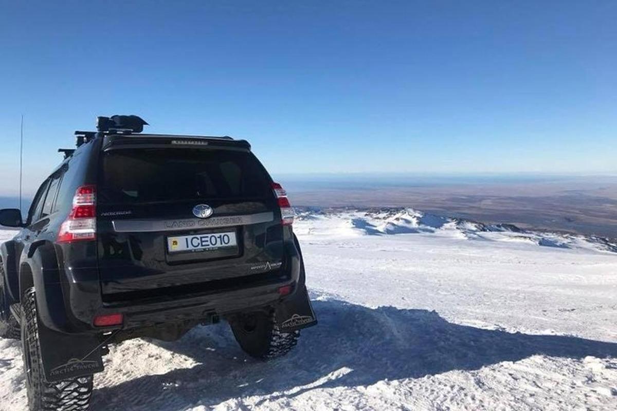 Un camión negro estacionado en la cima de una montaña cubierta de nieve