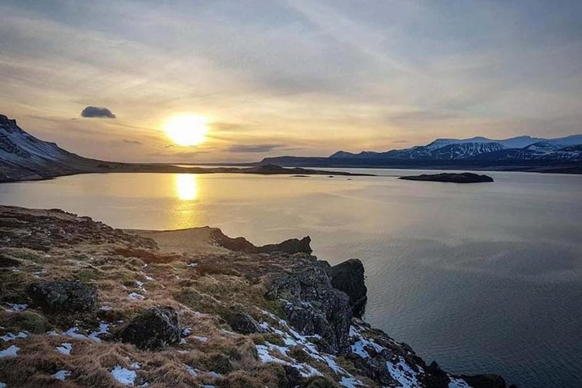 Una puesta de sol sobre un cuerpo de agua con montañas.