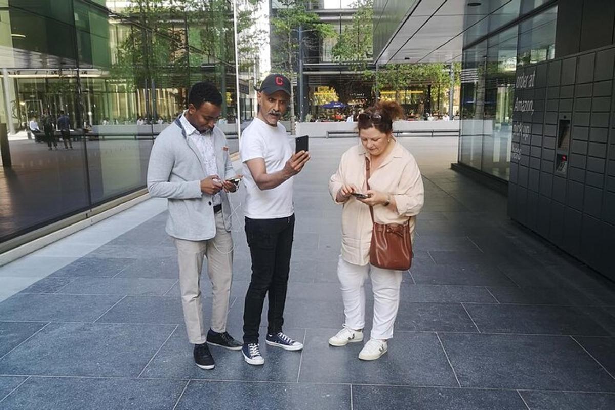 tre persone in piedi in un edificio che guardano i loro cellulari