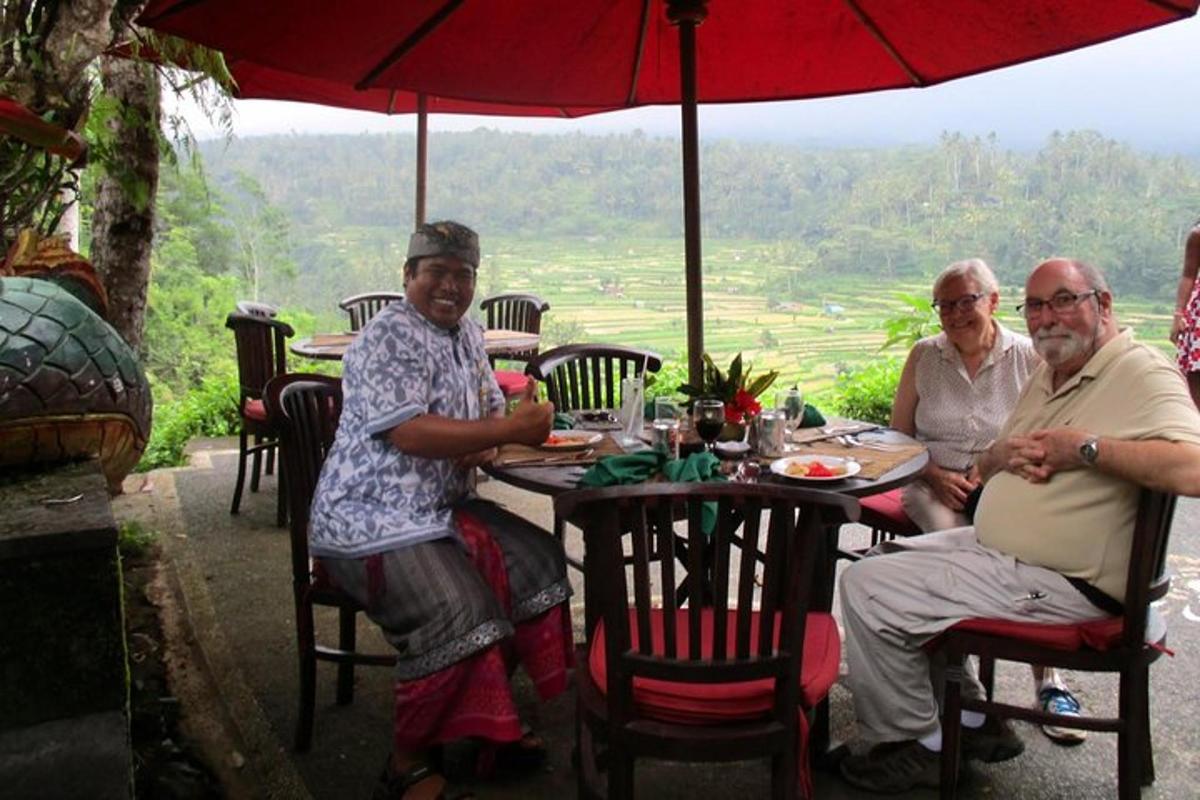 three older people sitting at a table under an umbrella