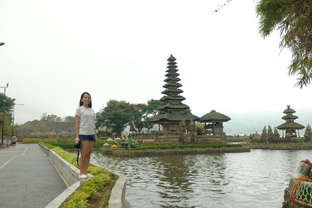 a woman standing next to a pond in front of a pagoda