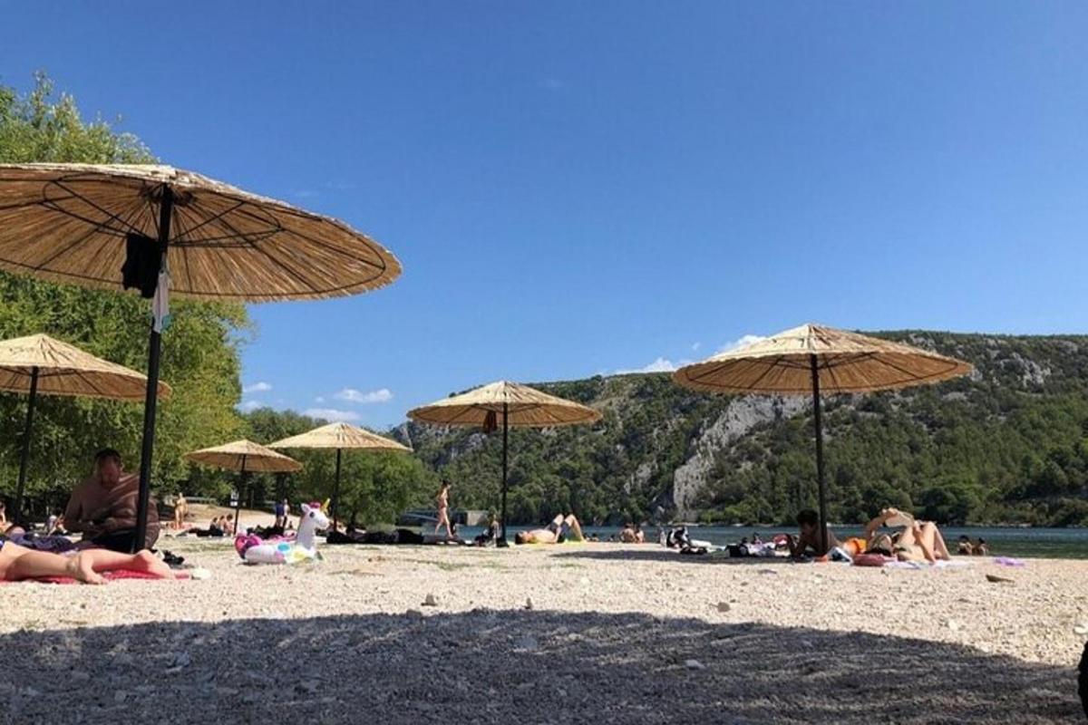 skupina lidí ležících na pláži se slunečníky