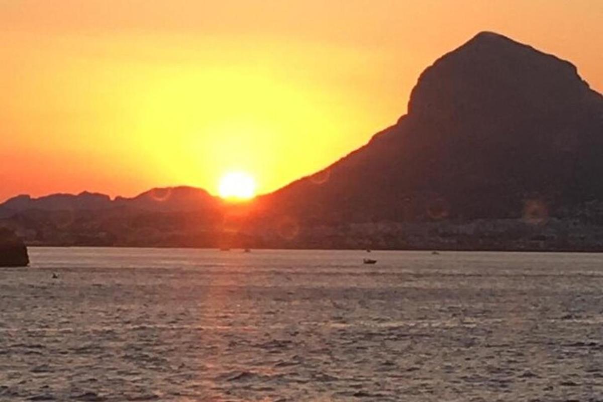 a sunset over a body of water with a mountain
