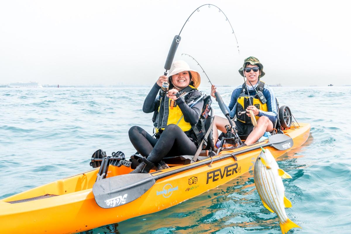 dua wanita dalam kayak kuning dengan seekor ikan