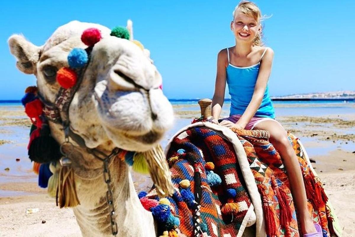 une jeune fille assise sur un chameau sur la plage
