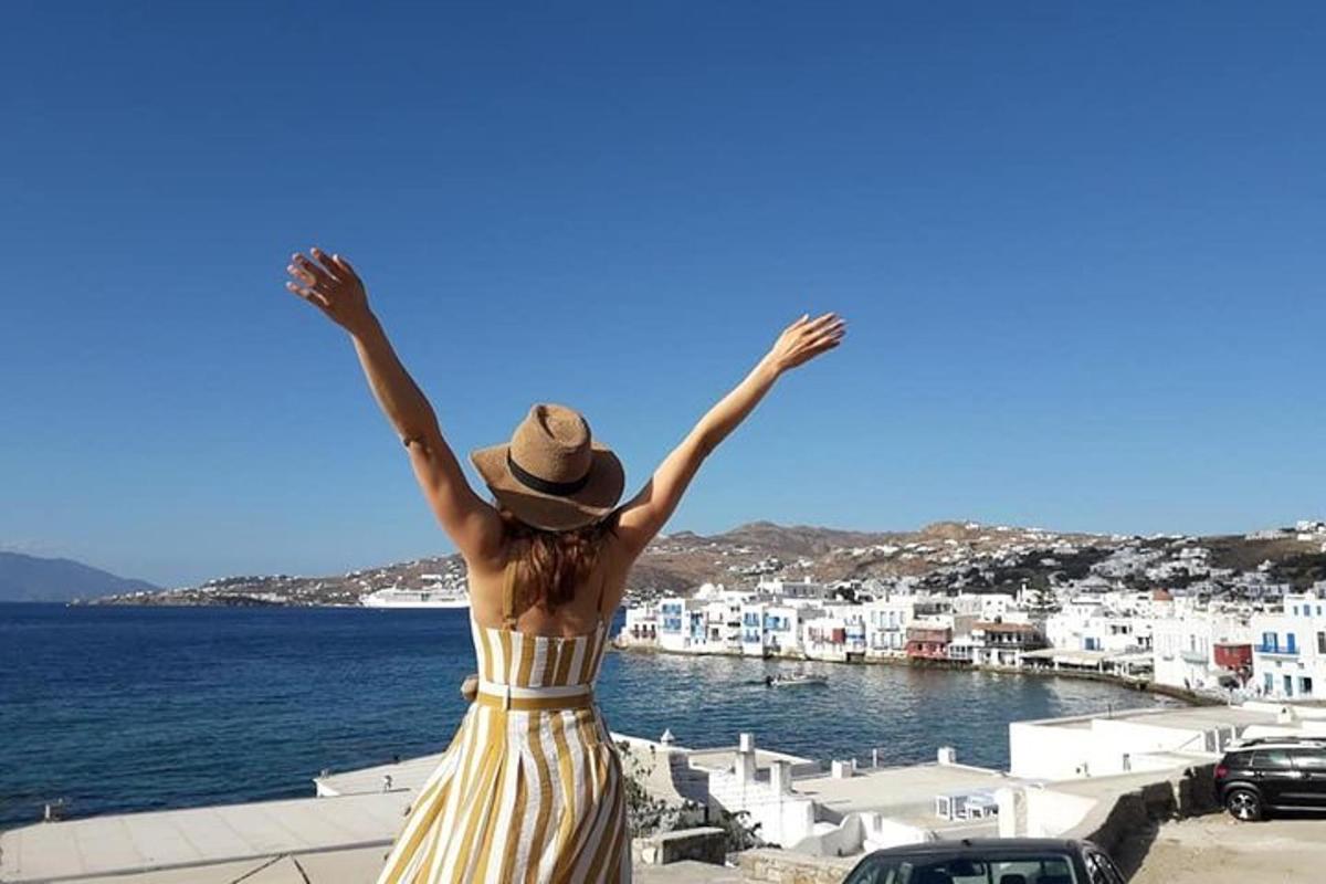 a woman in a yellow dress and hat looking at the water