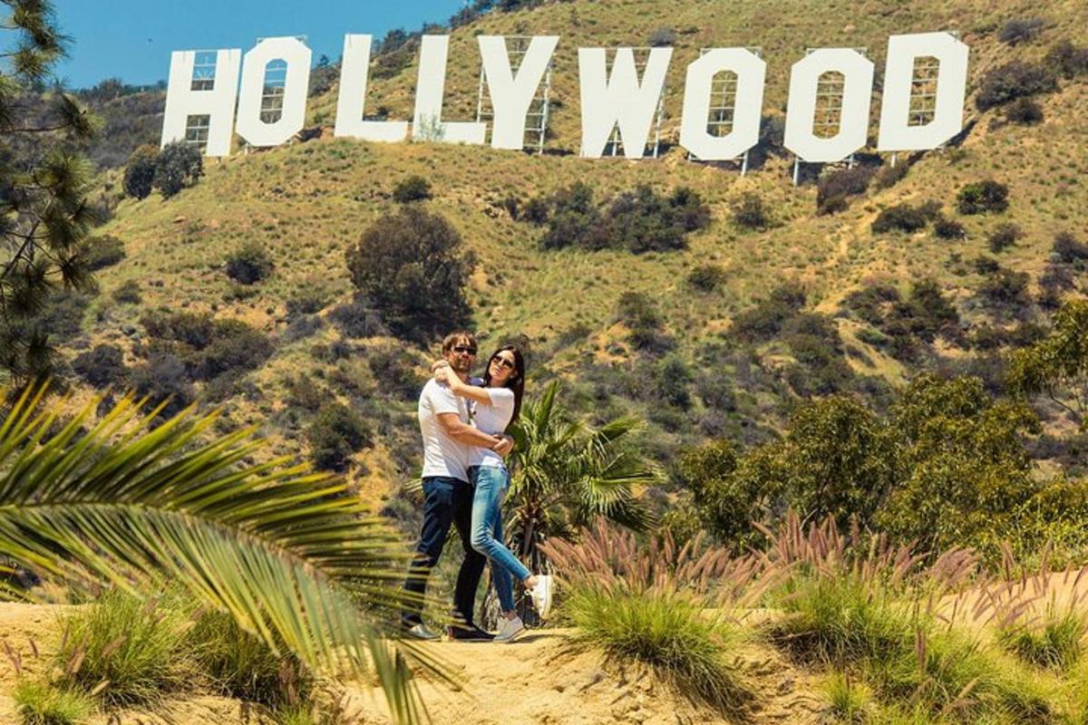 Muž a žena stojící před hollywoodským nápisem