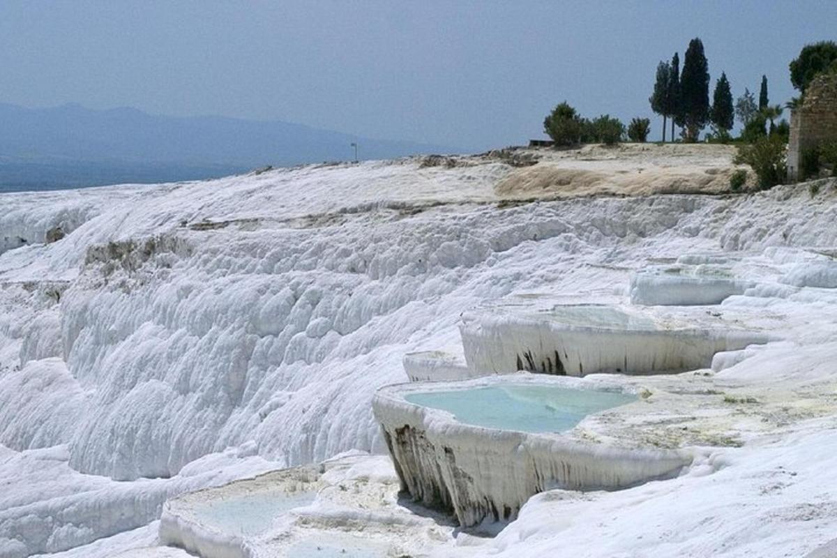 a snow covered hill with a blue pool of water