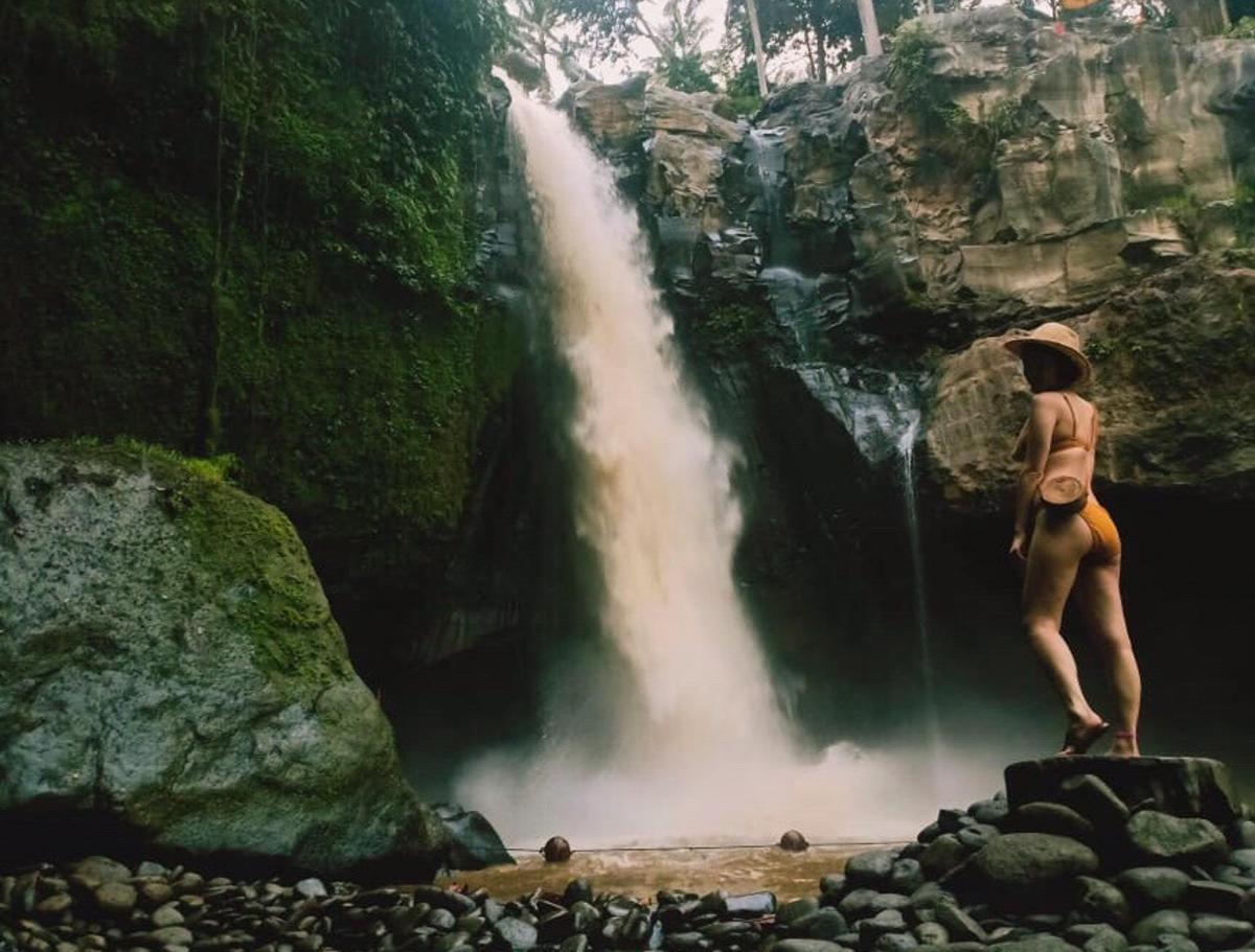 un uomo in piedi su una roccia di fronte a una cascata