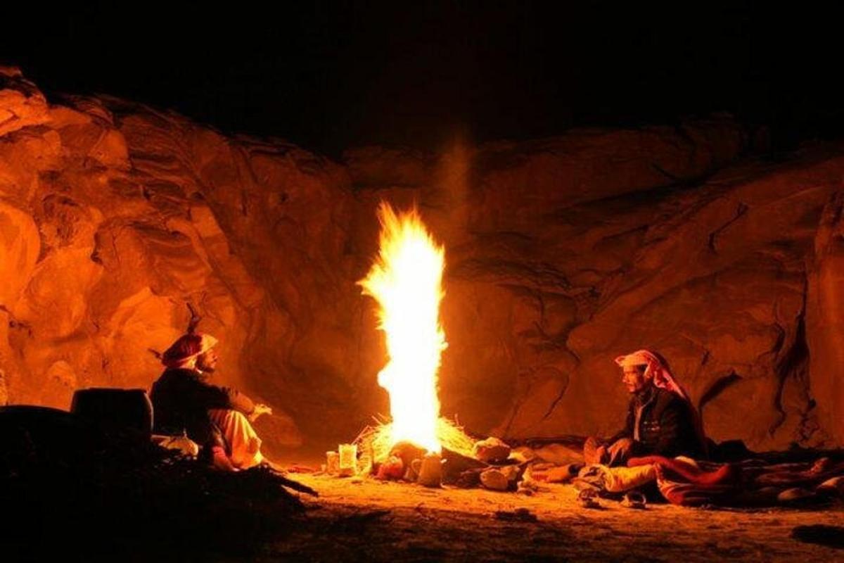 duas pessoas sentadas ao redor de uma fogueira em uma caverna