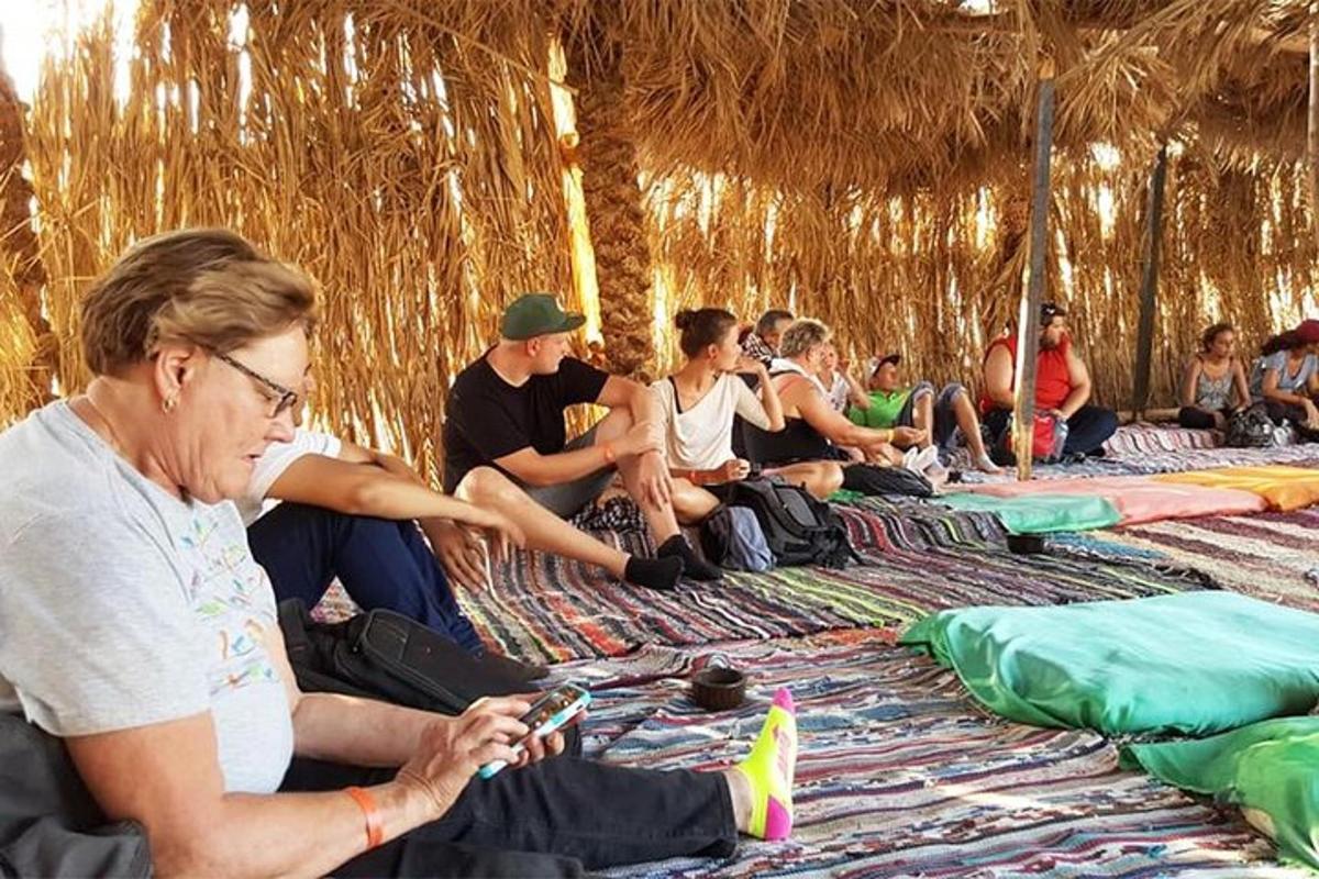 sekumpulan orang yang duduk di pantai melihat telefon bimbit mereka