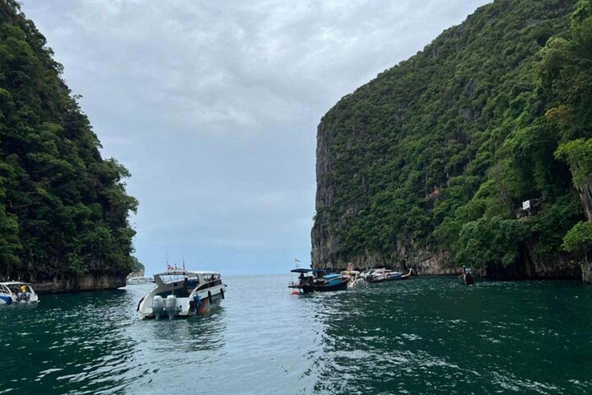 Dos barcos están atracados en el agua junto a una montaña.