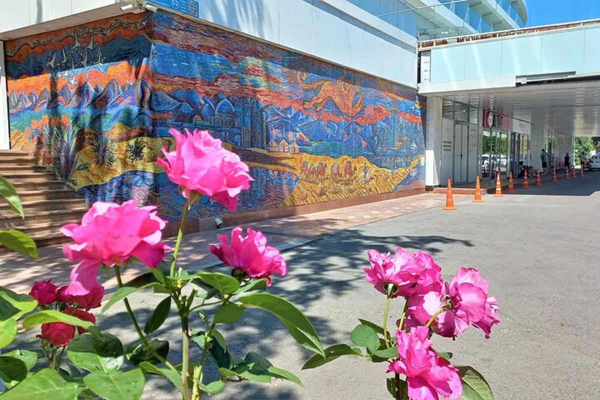 зид зграде са ружичастим цвећем испред мурала