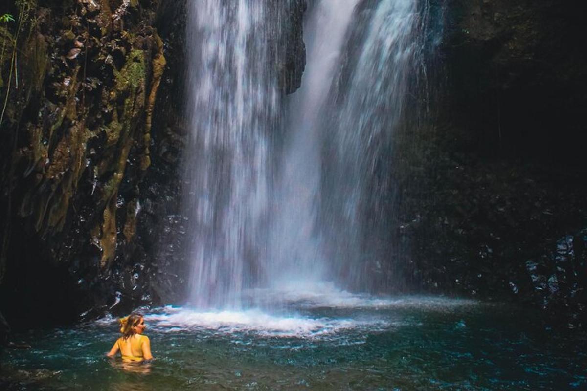 uma mulher parada na água em frente a uma cachoeira