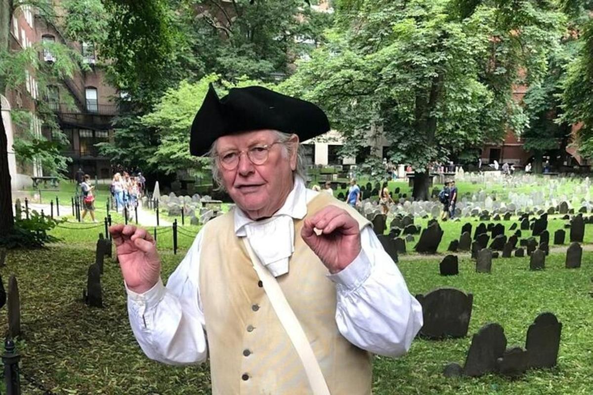 Un hombre mayor vestido de camarero en un cementerio.