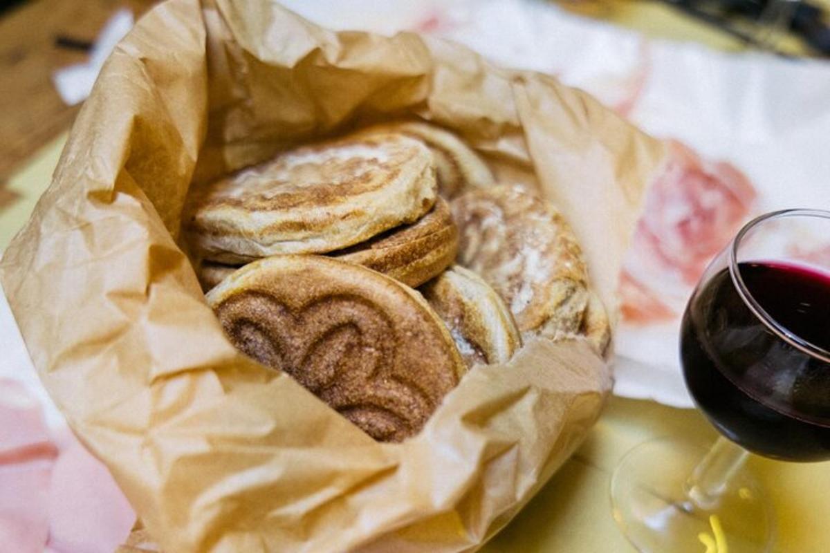 Una cesta de pan sobre una mesa con una copa de vino.