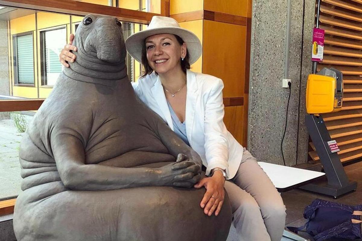 žena sedící vedle sochy medvěda