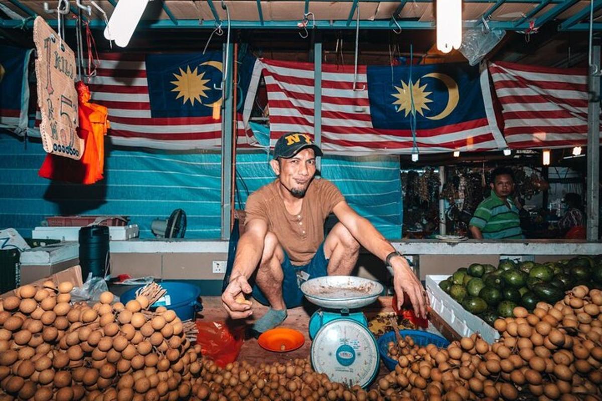a man sitting in front of a fruit stand
