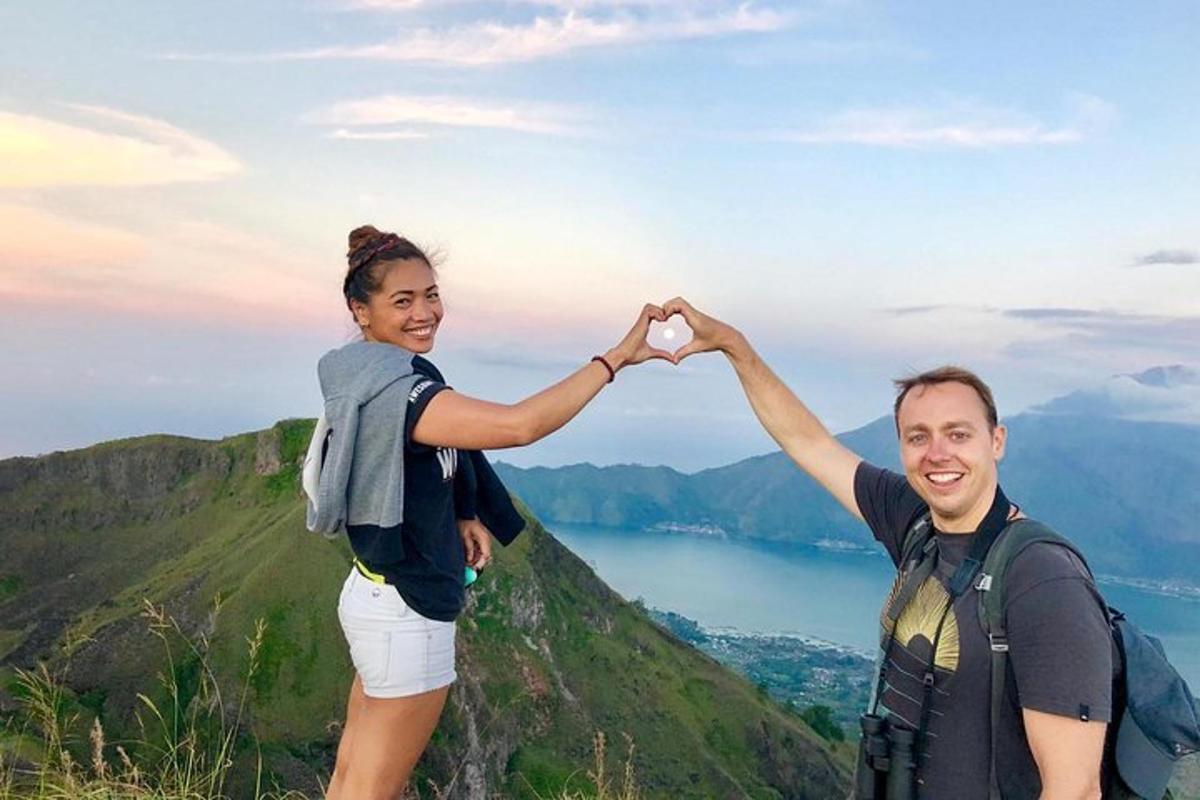 um homem e uma mulher fazendo um sinal de coração em uma montanha