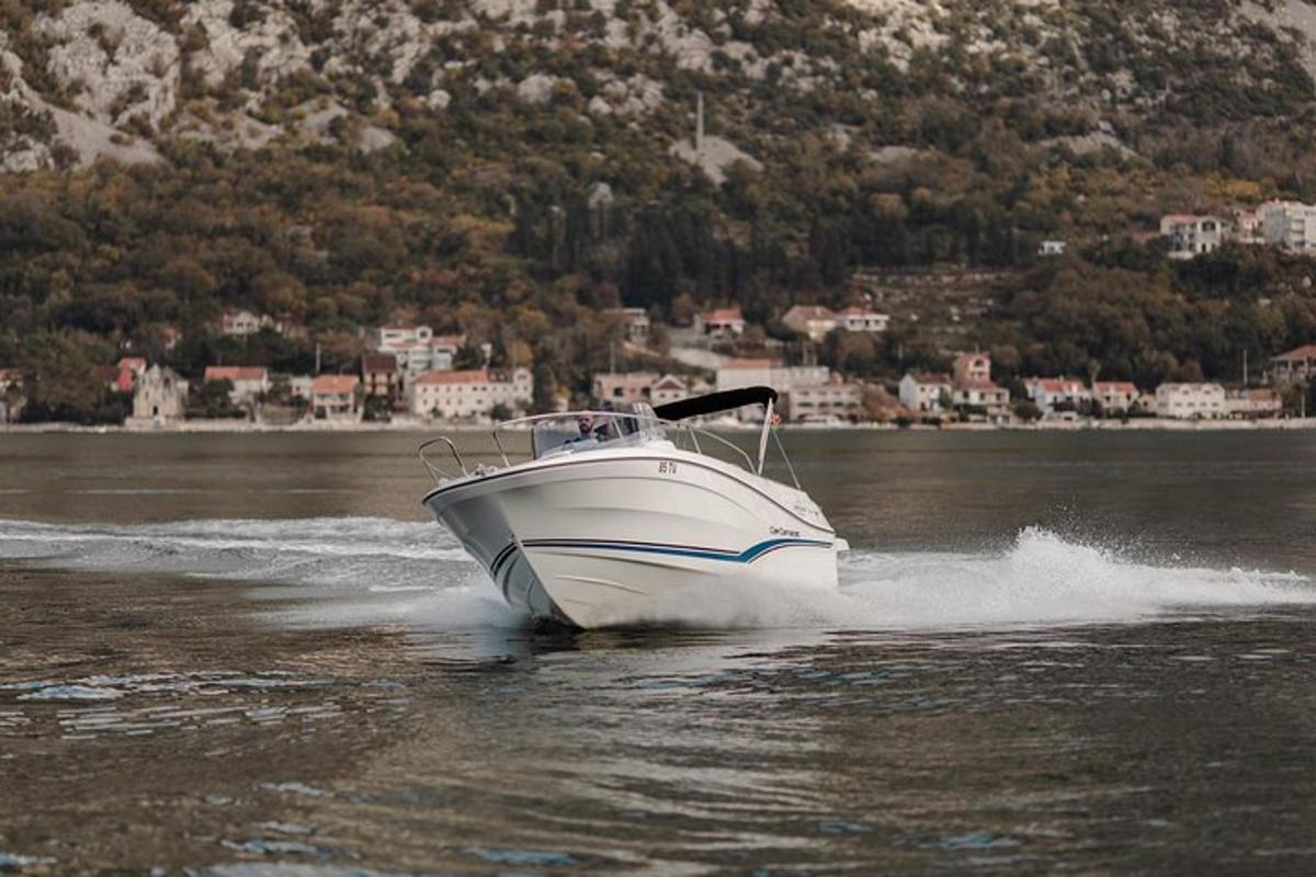 a white boat on the water with a town in the background