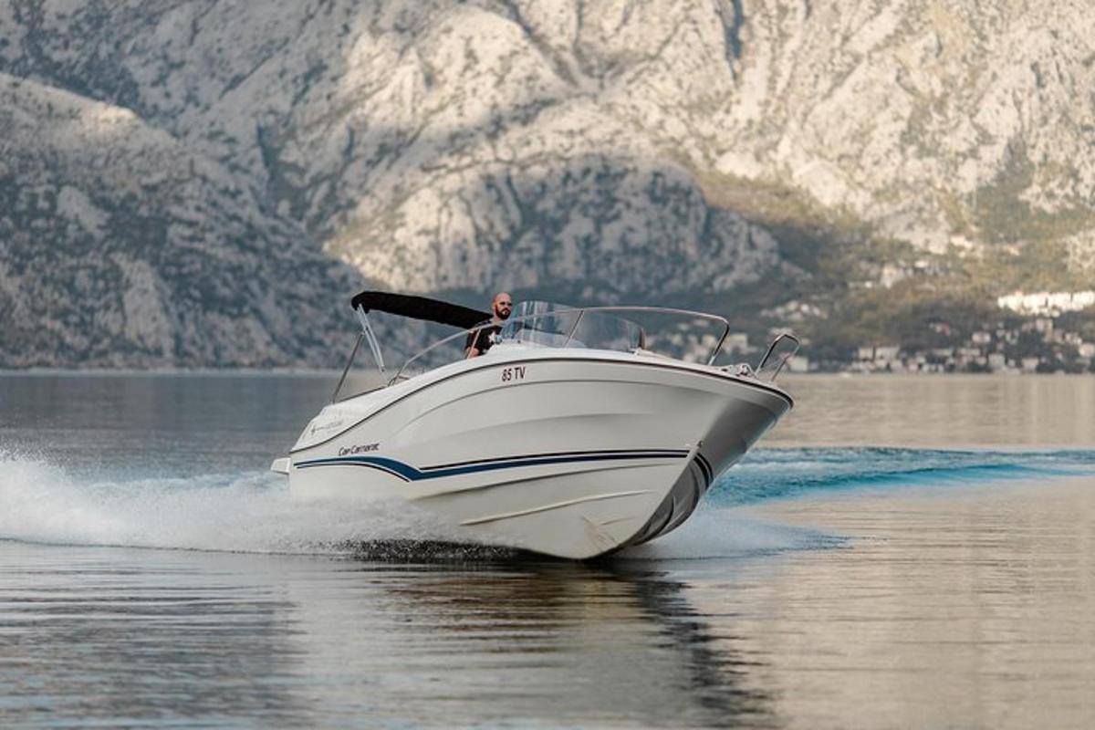 a white boat on the water with mountains in the background