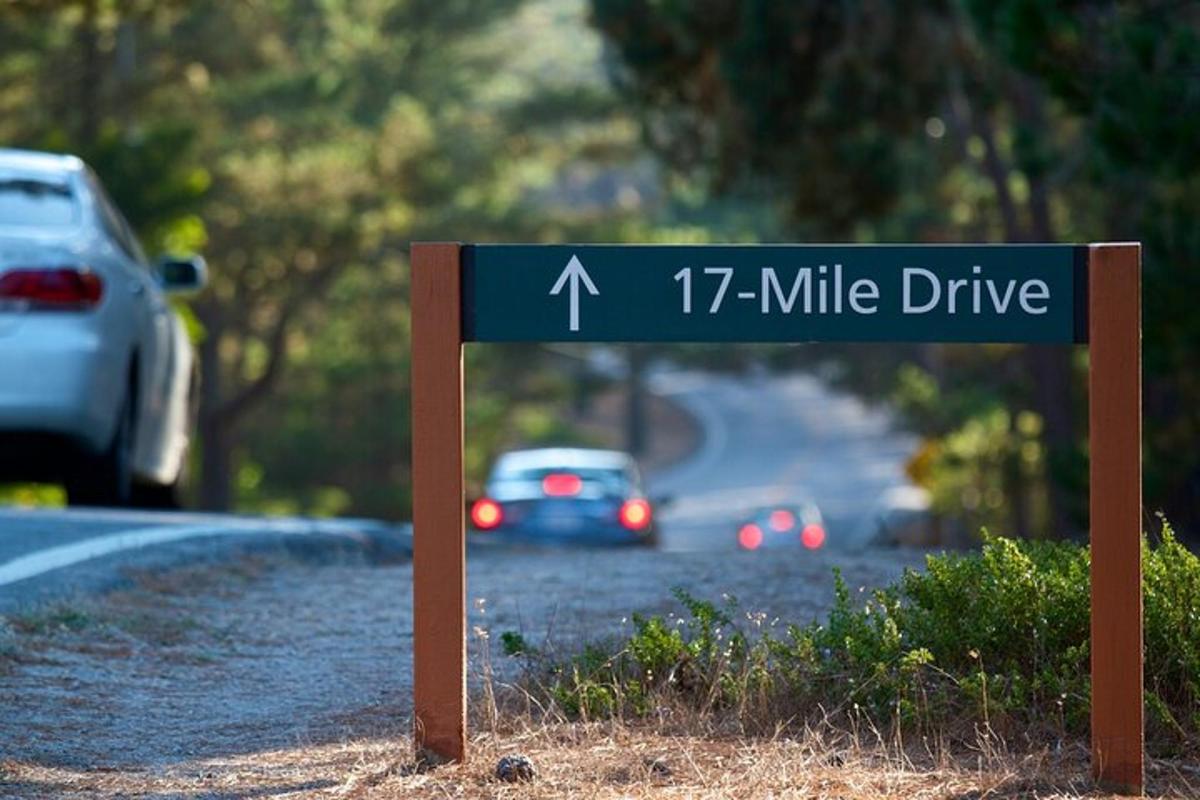a street sign on the side of a road with a car