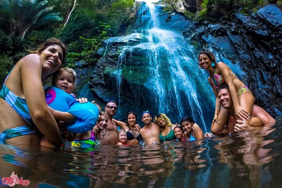 a group of people in the water near a waterfall