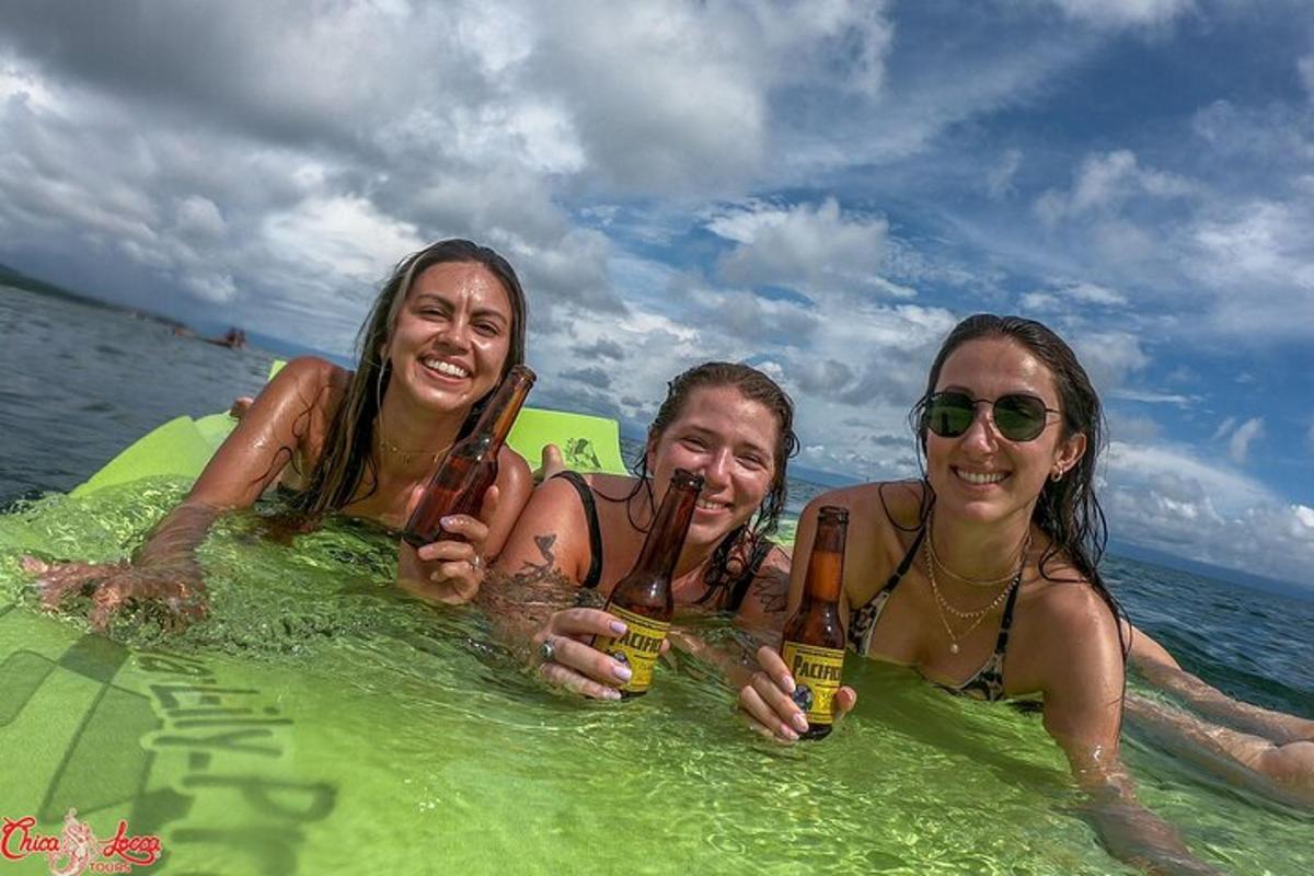 three women are laying in the water holding beer