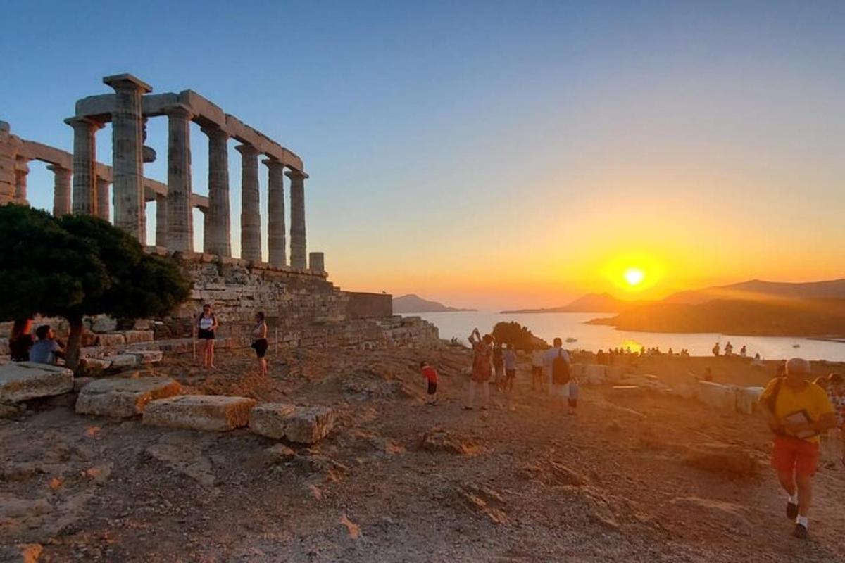 a group of people walking on a hill with the sunset