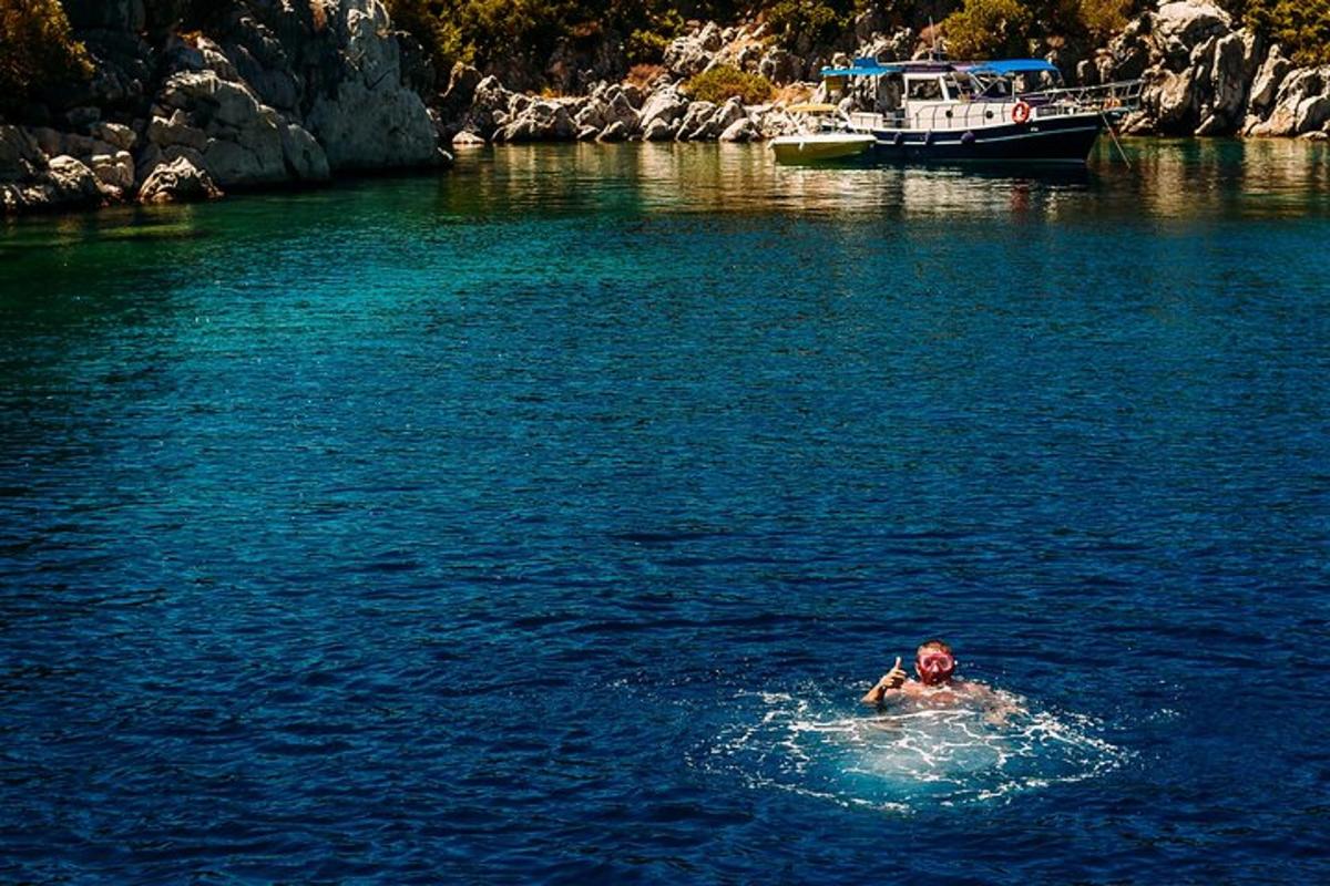 a man swimming in a body of water with a boat