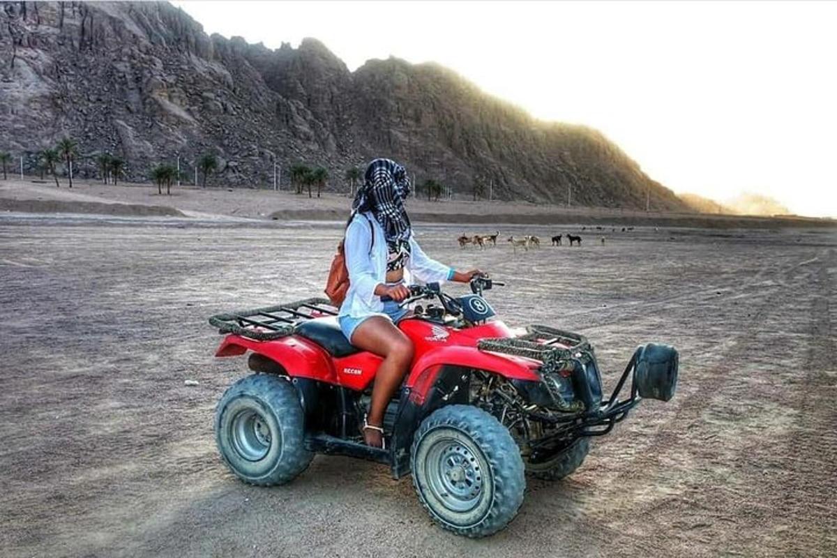a person riding a red atv on the beach