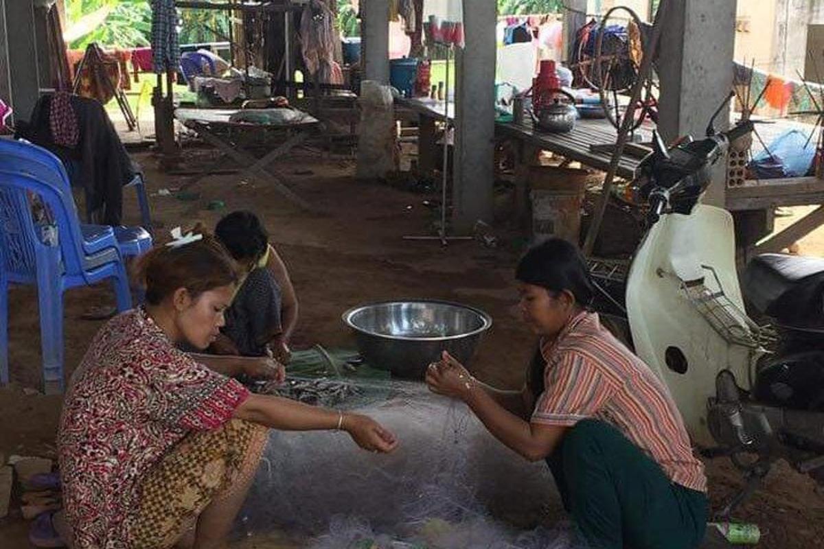 a group of women preparing food on the ground