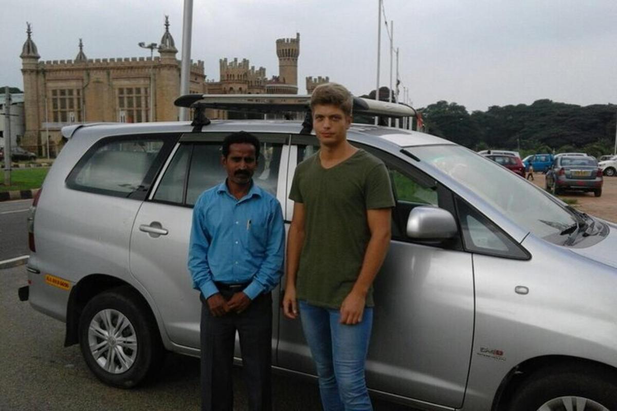 two men standing in front of a silver car