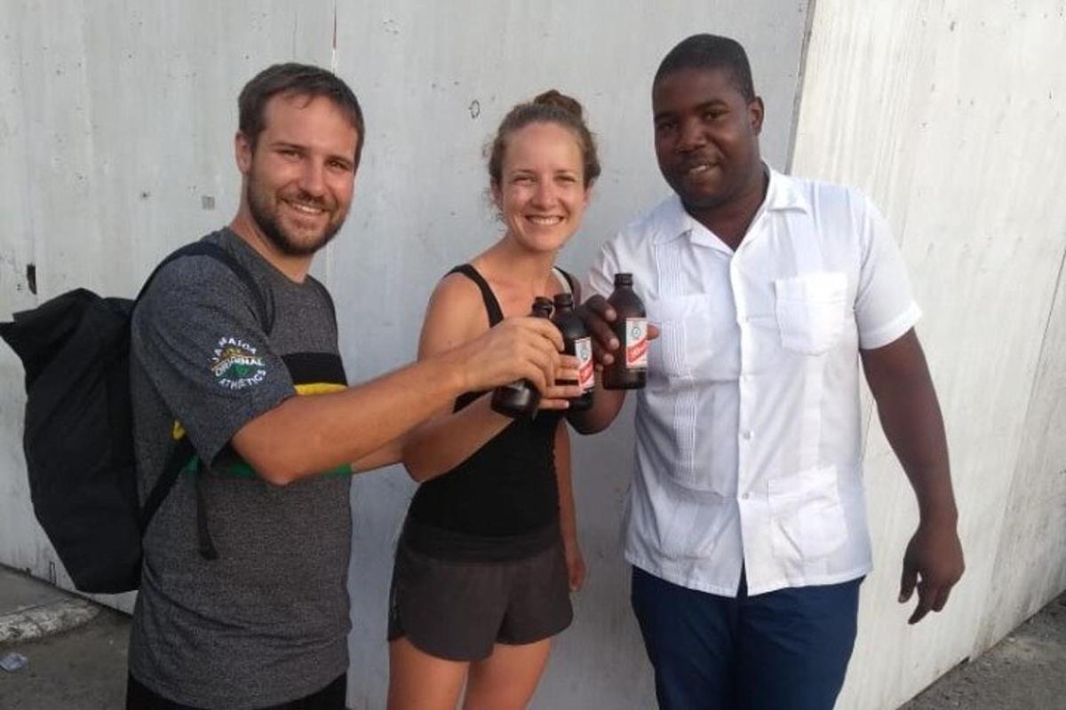 two men and a woman holding bottles of beer