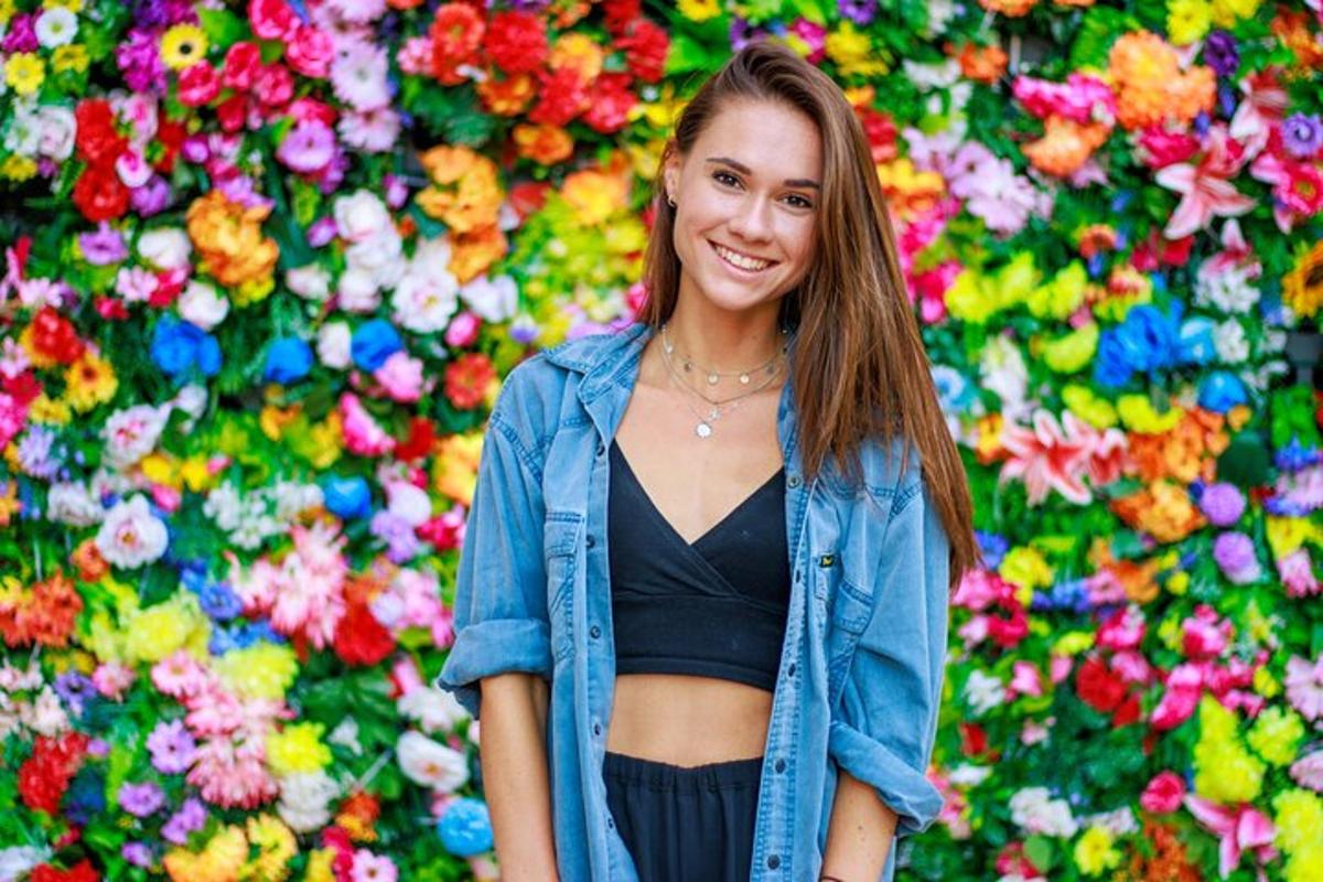 una donna in piedi davanti a un muro di fiori