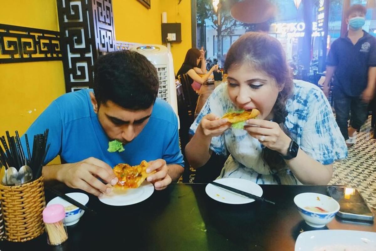 a man and woman sitting at a table eating pizza