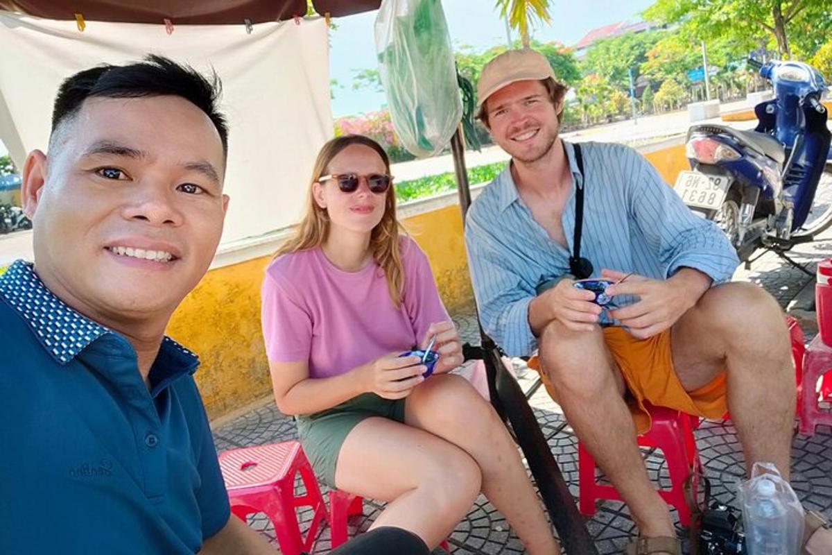 a group of three people sitting under a tent