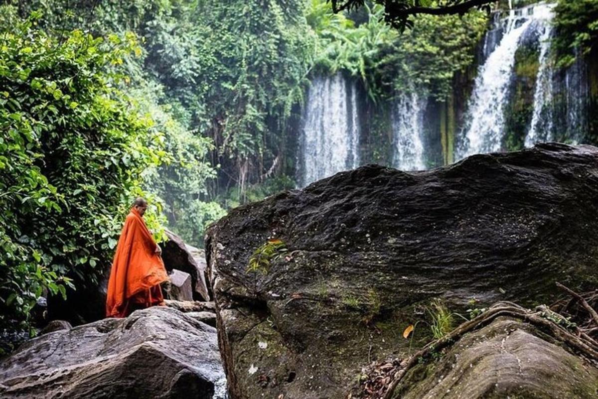 a woman standing on a rock in front of a waterfall