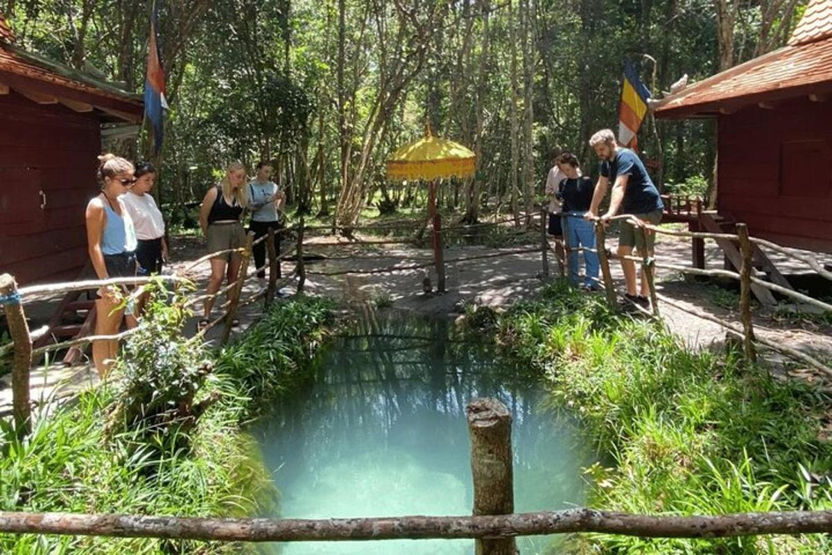 a group of people standing around a small pond