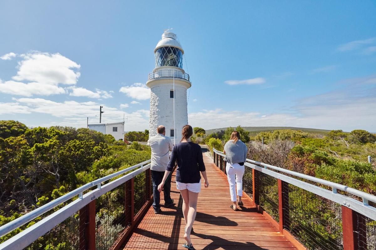 people walking on a bridge towards a lighthouse