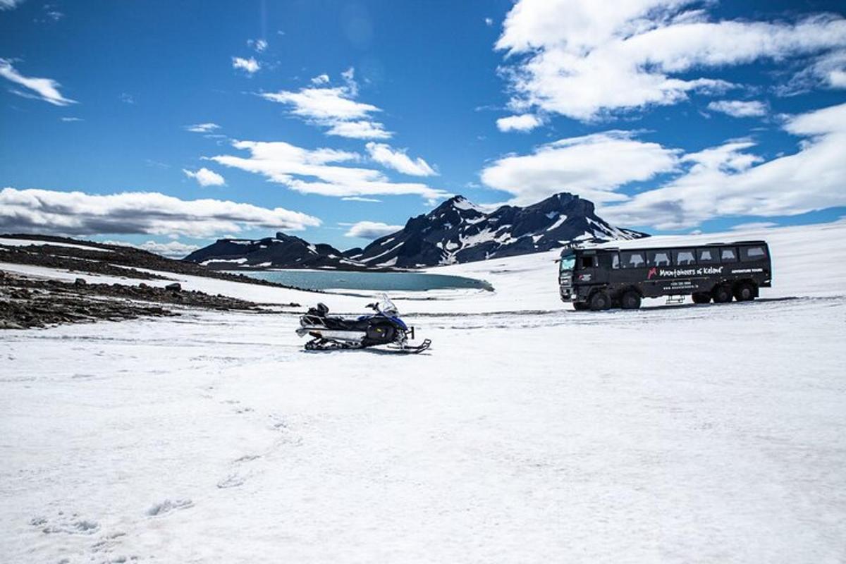 Un autobús estacionado en la nieve junto a una moto de nieve.