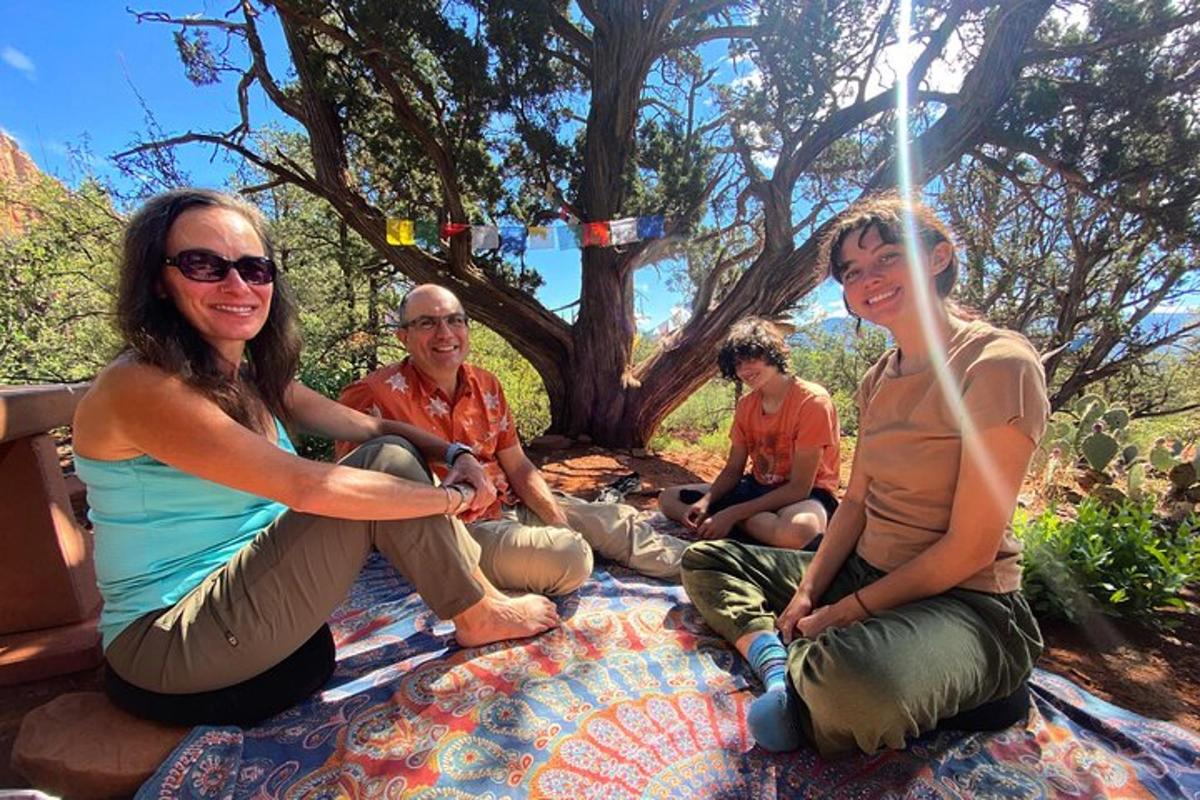un gruppo di persone sedute su una coperta sotto un albero