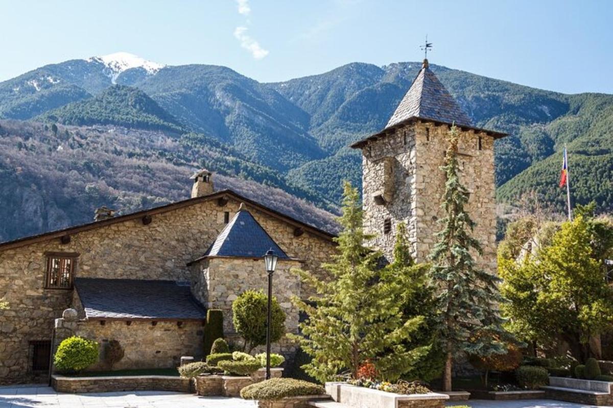 a stone building with a tower with mountains in the background