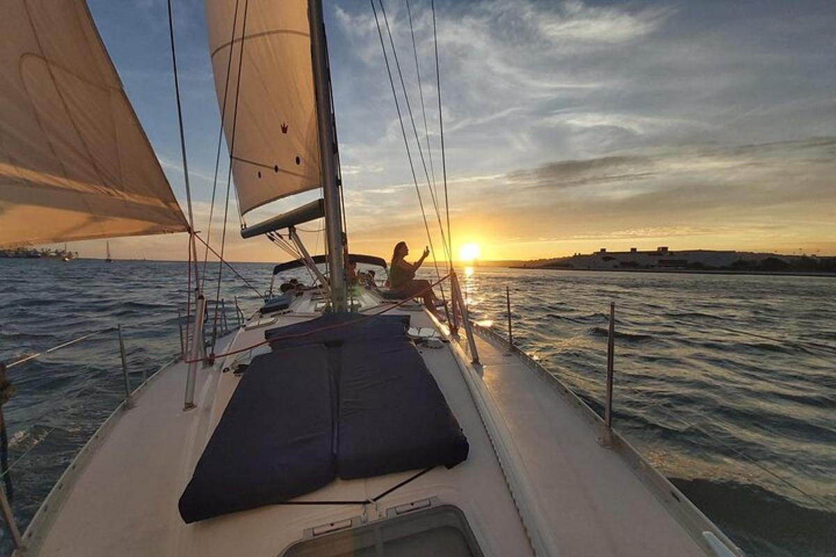 una persona su una barca a vela in acqua al tramonto