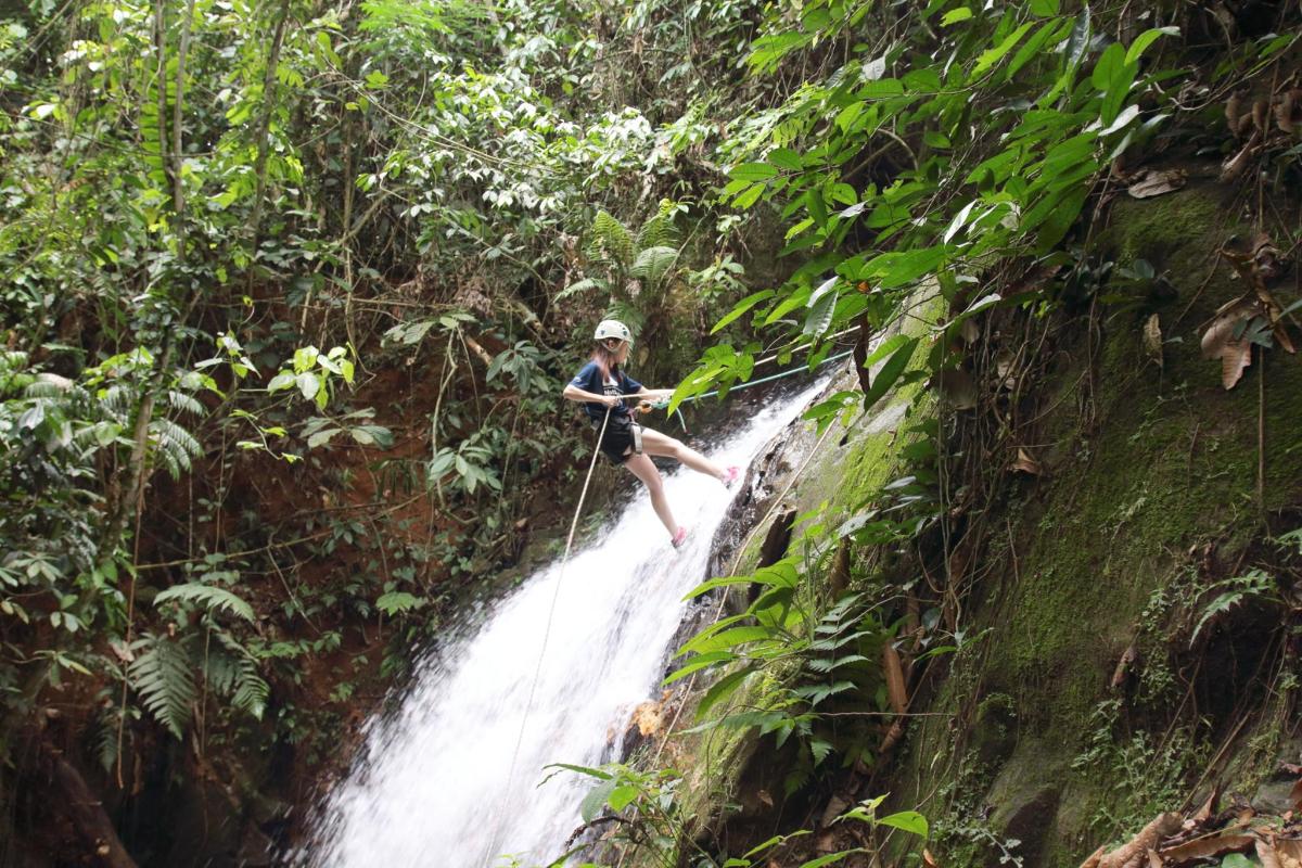 a woman on a zip line over a waterfall