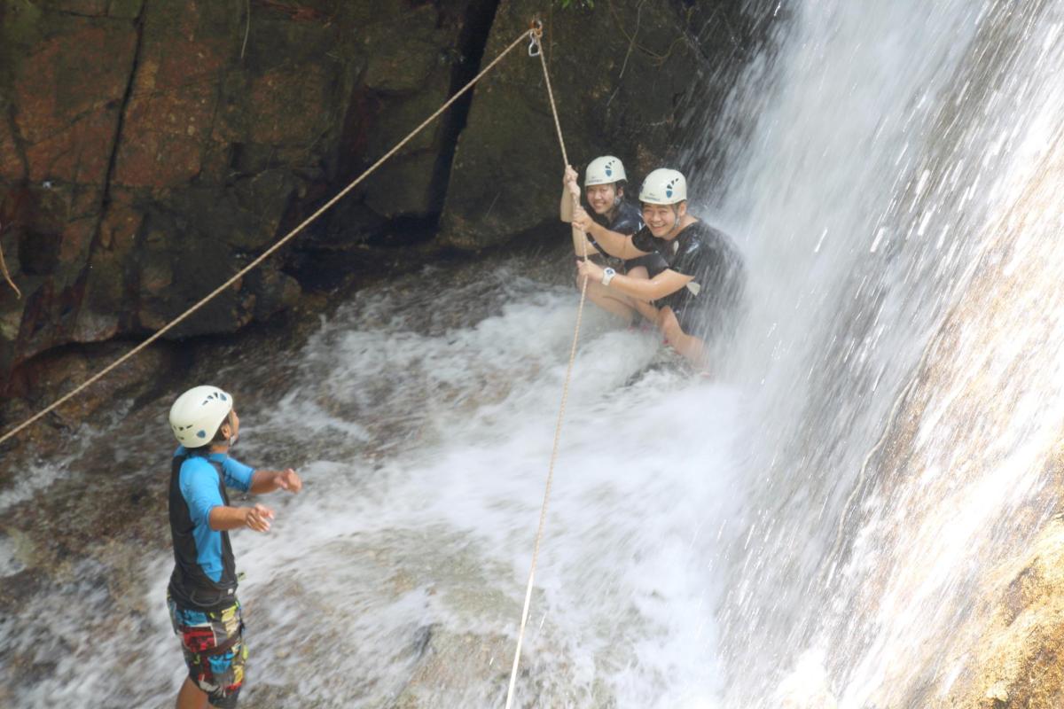 a group of three people rappelling down a waterfall