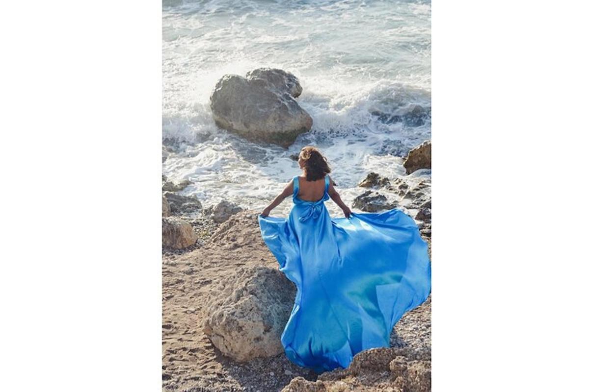una donna in un vestito blu in piedi sulla spiaggia