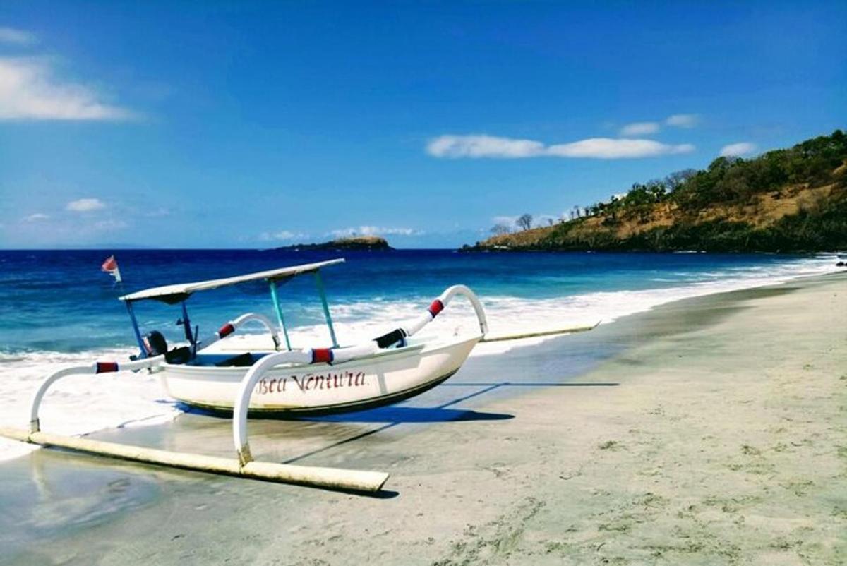 a boat sitting on a beach next to the ocean